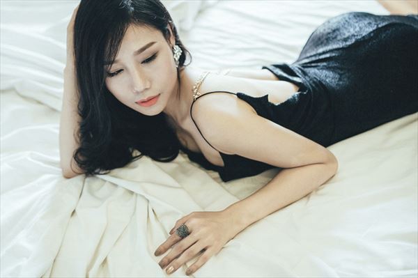 ベッドの上で寝そべる黒いドレスの女性